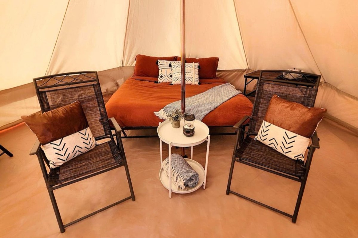 The interior of a furnished tent, with bed and chairs
