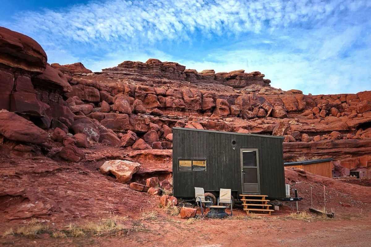 A timber cabin set among red rock boulders at the base of the cliffs